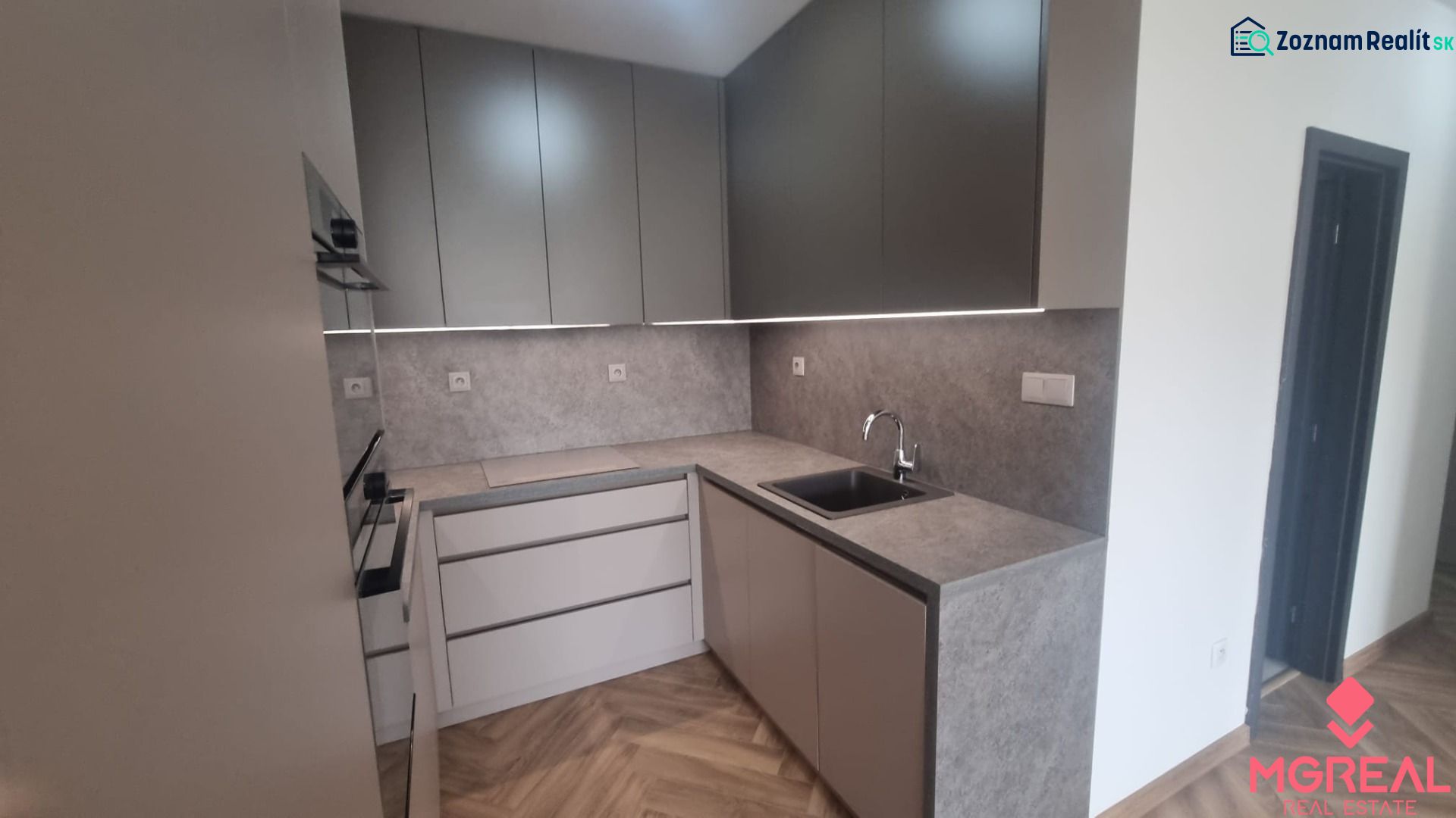2-izbový moderný byt, s garážovým státím  novostavba, Coboriho ulica - Kuchyňa s podlahou s dreveným dekorom v 2-izbovom byte, sivé skrinky, vstavaná rúra.
