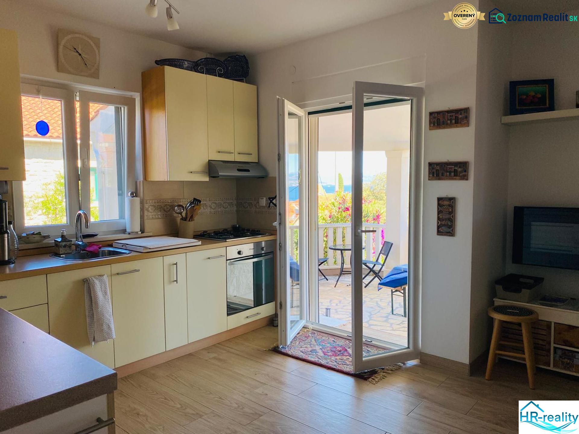 Brač(HR)- zariadený apartmán s výhľadom na more - Kuchyňa v rekreačnom apartmáne s podlahou s dreveným dekorom a prístupom na terasu.