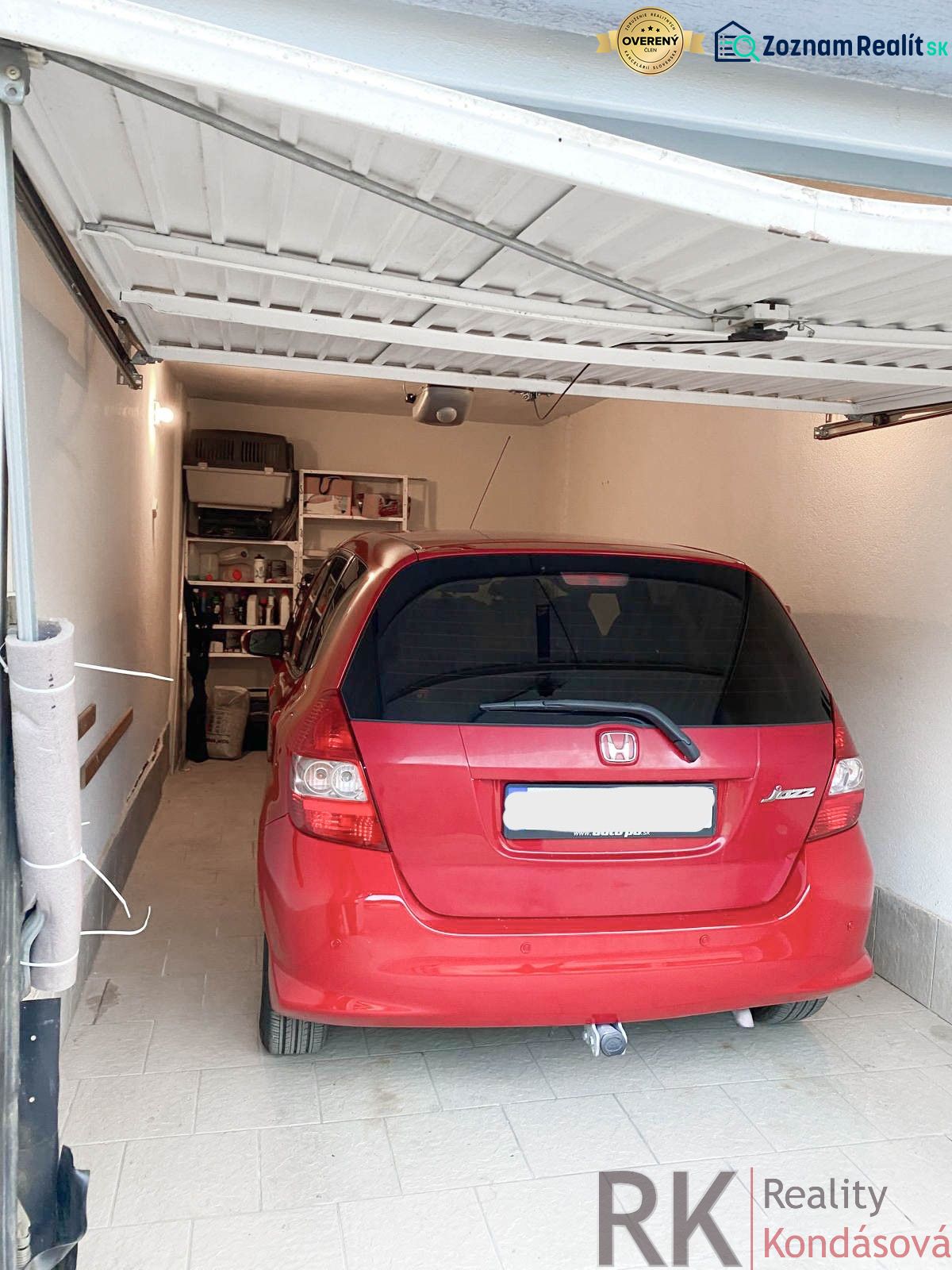 Garáž na prenájom- Staré mesto- Belanská, automatická brána - Červené auto zaparkované v garáži s regálmi na stene, podlaha z dlažby.
