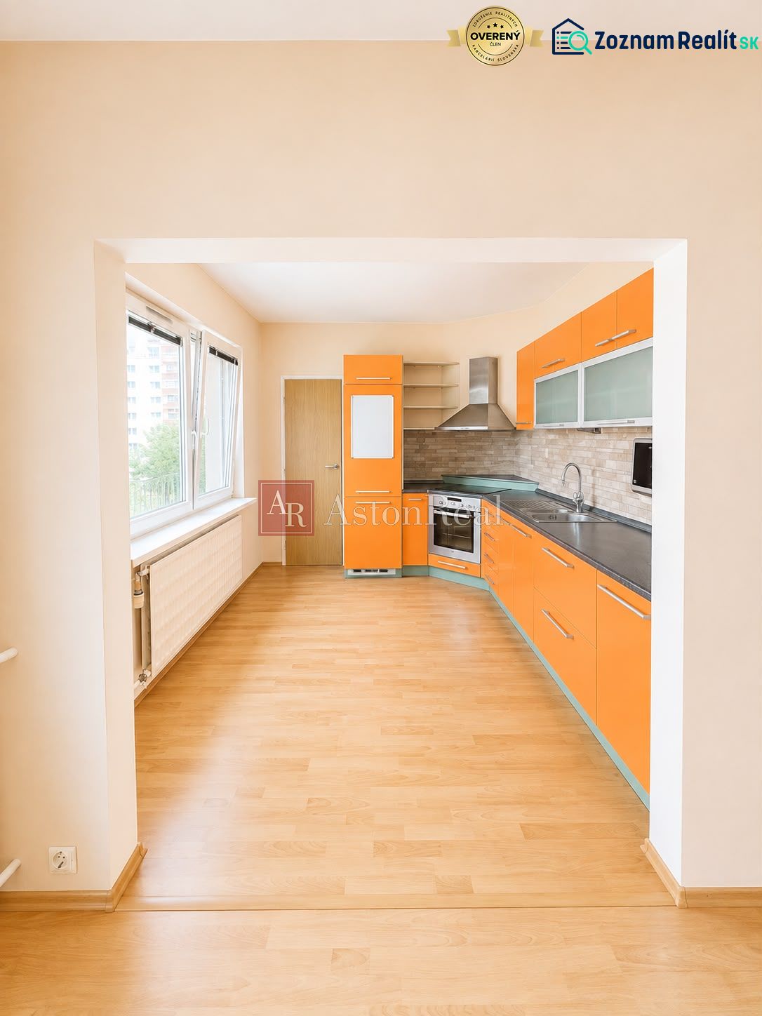 Predaj! slnečný 3-izbový byt s loggiou 74 m² Podbreziny - LM - Kuchyňa so vstavanými spotrebičmi, výrazným oranžovým nábytkom a podlahou s dreveným dekorom v 3-izbovom byte.