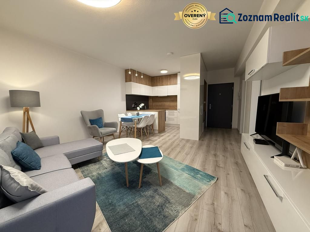 Nové skolaudované byty a apartmány vo Vajnoroch. - Svetlá obývacia izba s kuchynským kútom a podlahou s dreveným dekorom.