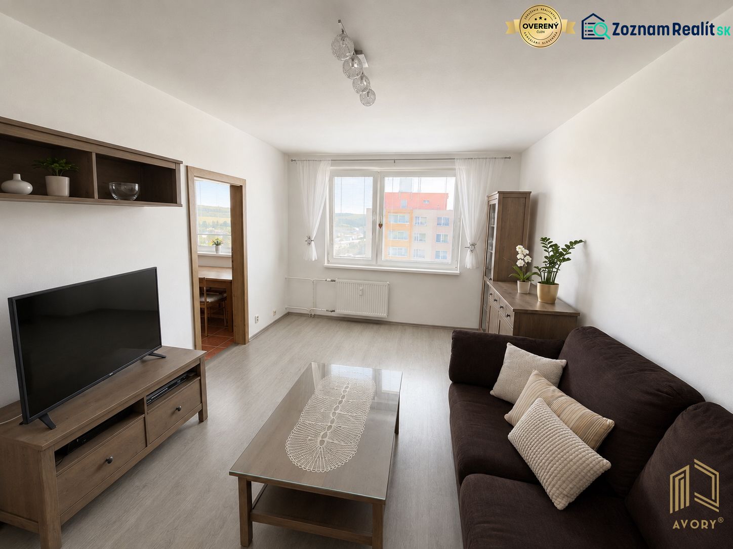3-izb. byt (74m2), balkón, komora, Senica - Sotiná - Obývacia izba v 3-izbovom byte s podlahou s dreveným dekorom a tmavou sedačkou.