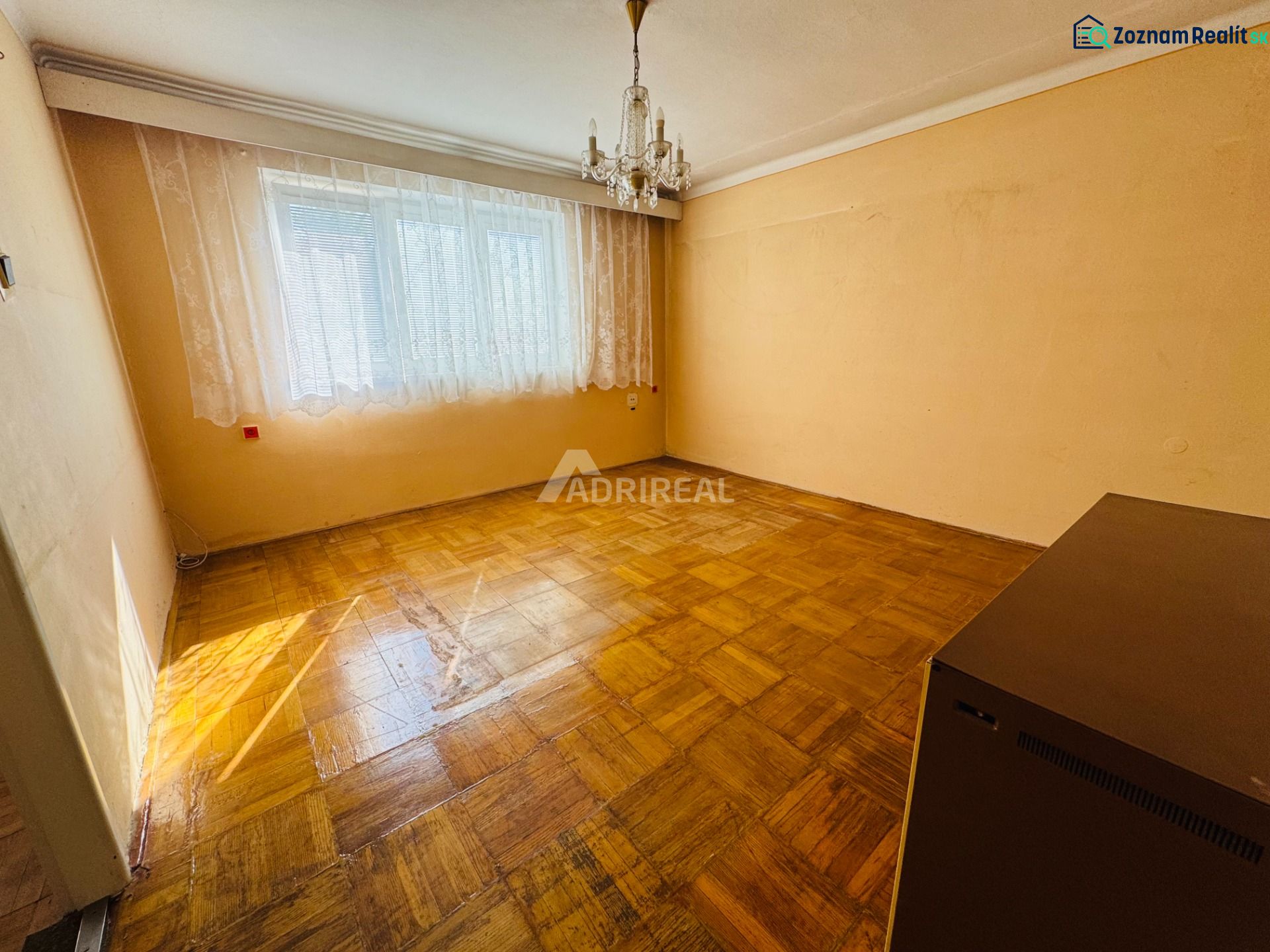 PREDAJ: 2i byt; 65 m2; CENTRUM - KRUPINA; 84.500 €  - Izba v 2-izbovom byte s krištáľovým lustrom a podlahou s dreveným dekorom.