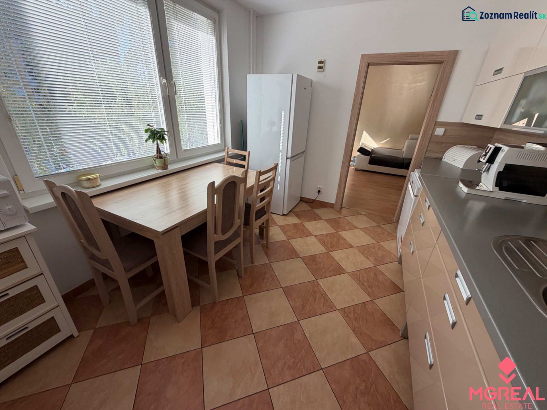 3 izbový byt s balkónom Topoľčany  - Kuchyňa v 3-izbovom byte s kachličkovou podlahou, jedálenským stolom a spotrebičmi.