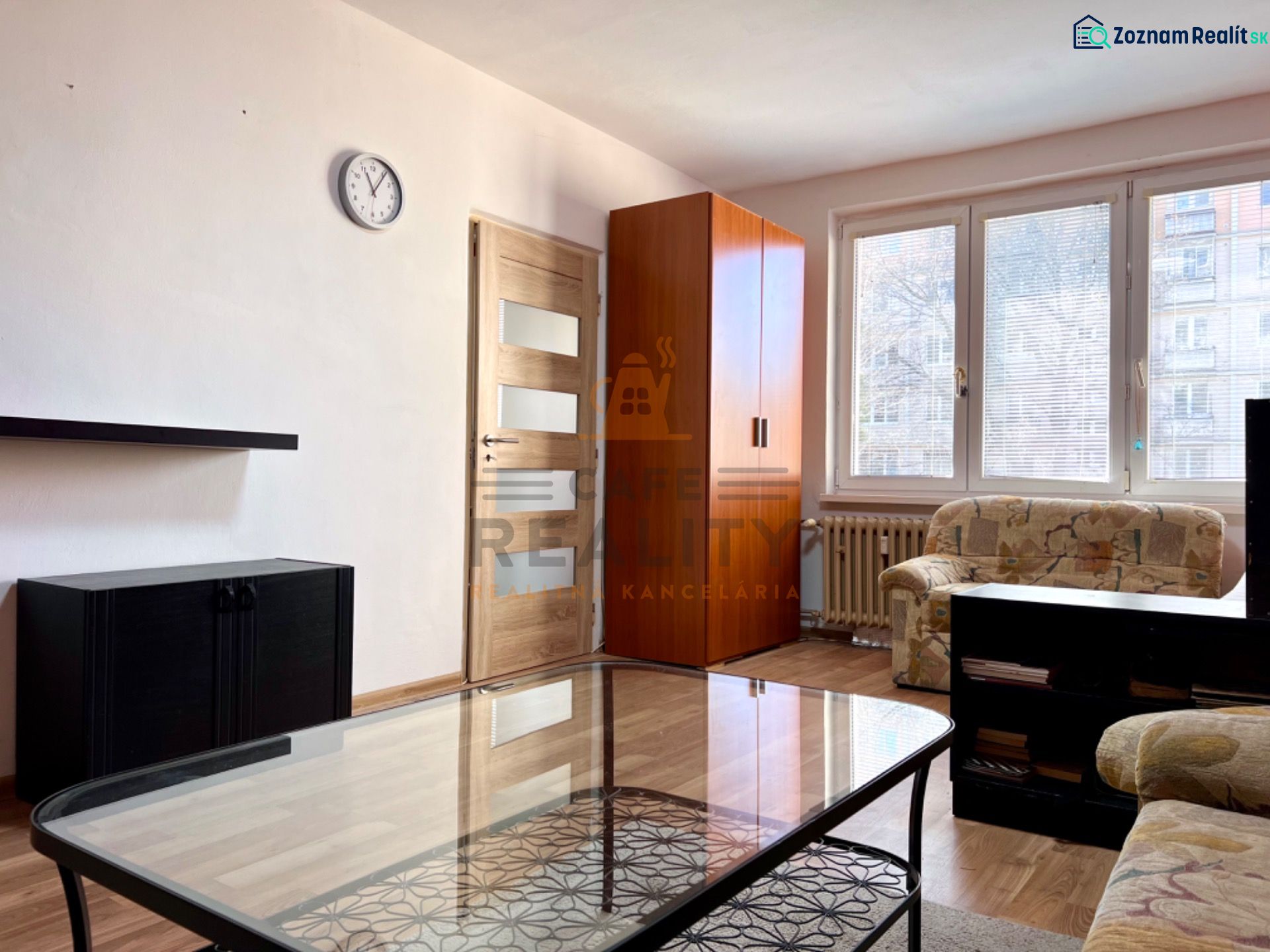 Na predaj 2 izbový byt, 47 m2, Bratislava, Nové Mesto, Piešťanská ul. - Obývacia izba s pohovkou, skriňou a podlahou s dreveným dekorom v 2-izbovom byte.