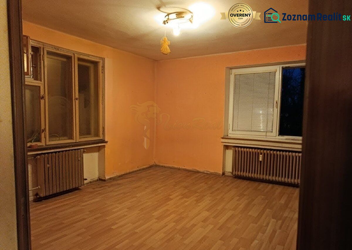 Veľký 2-izb. byt, Olbrachtova ul., Nové Mesto - Izba v 2-izbovom byte, oranžové steny, podlaha s dreveným dekorom, radiátory.