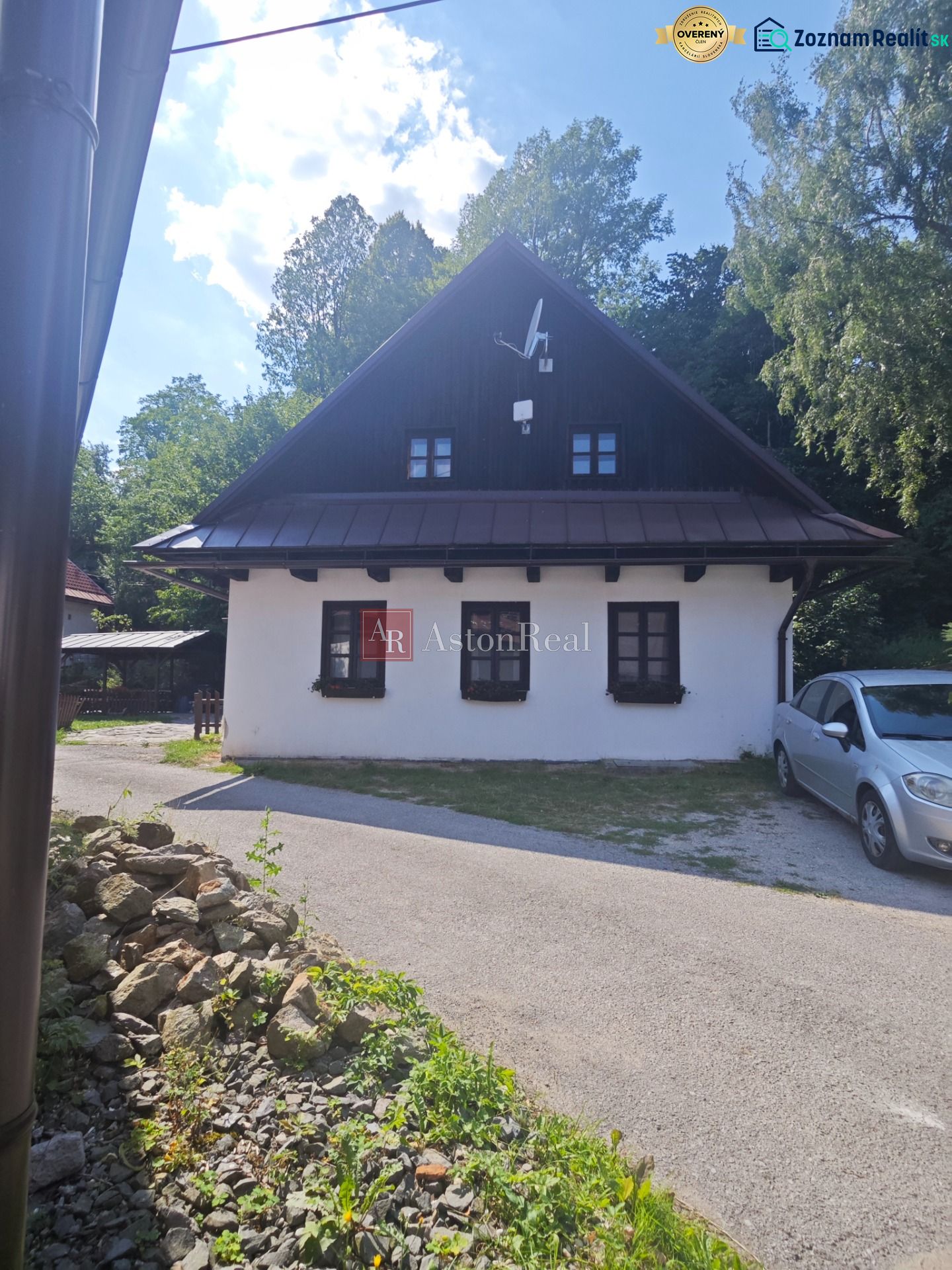 Predaj: Štýlová chalupa v srdci Španej Doliny miesto s atmosférou  - Chata v Španej Doline s bielou fasádou a satelitnou anténou, obklopená zeleňou.