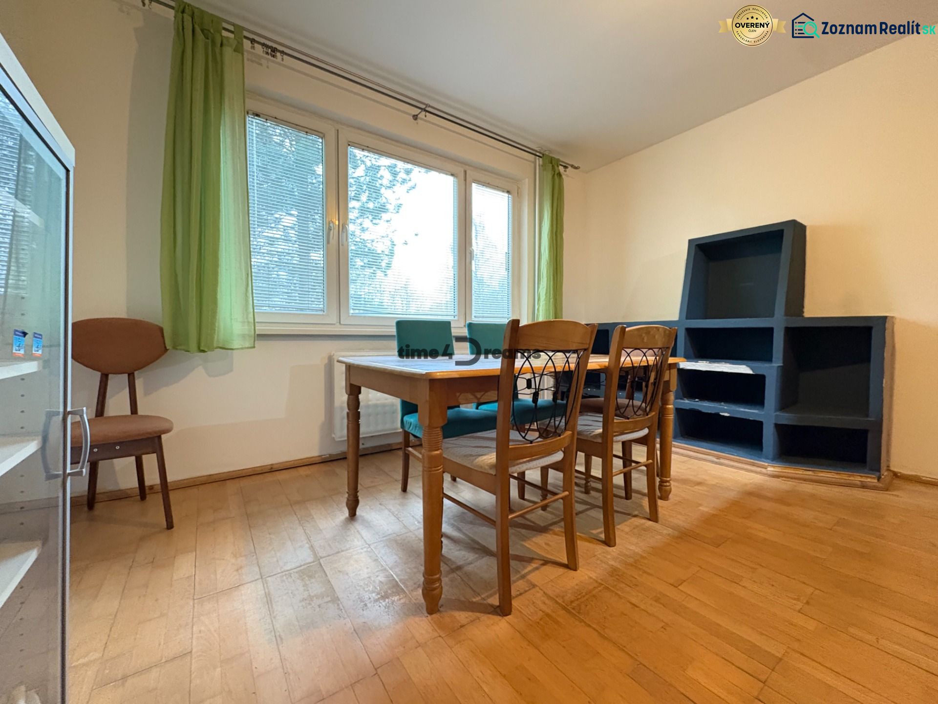 Na predaj: CENTRUM: 3 izb.byt + PIVNICA - Izba 3-izbového bytu s podlahou s dreveným dekorom, stolom a stoličkami.