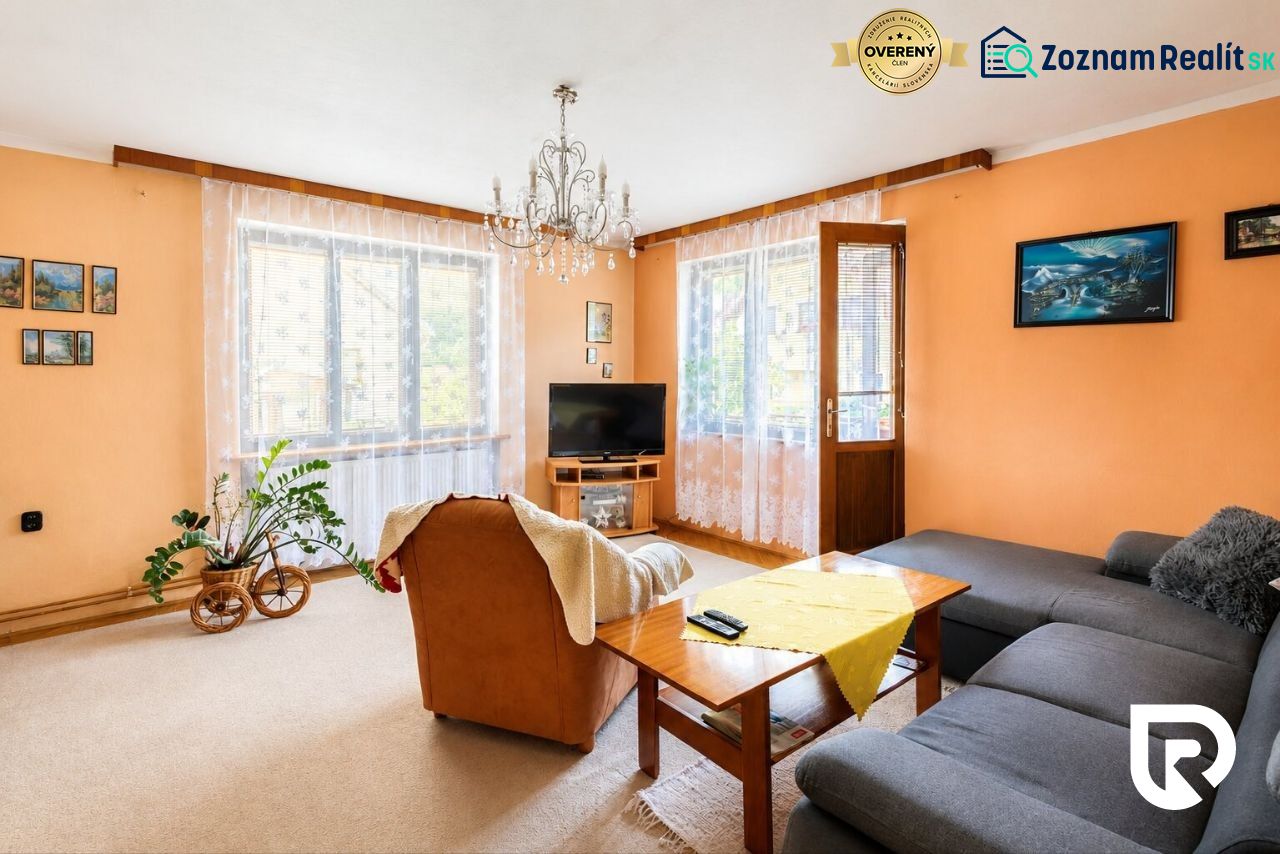 3-IZBOVÝ BYT 90 m² V RODINNOM DOME | POVAŽSKÝ CHLMEC - Žilina - Obývacia izba s krémovými stenami, oranžovým kreslom a šedou sedačkou v rodinnom dome.