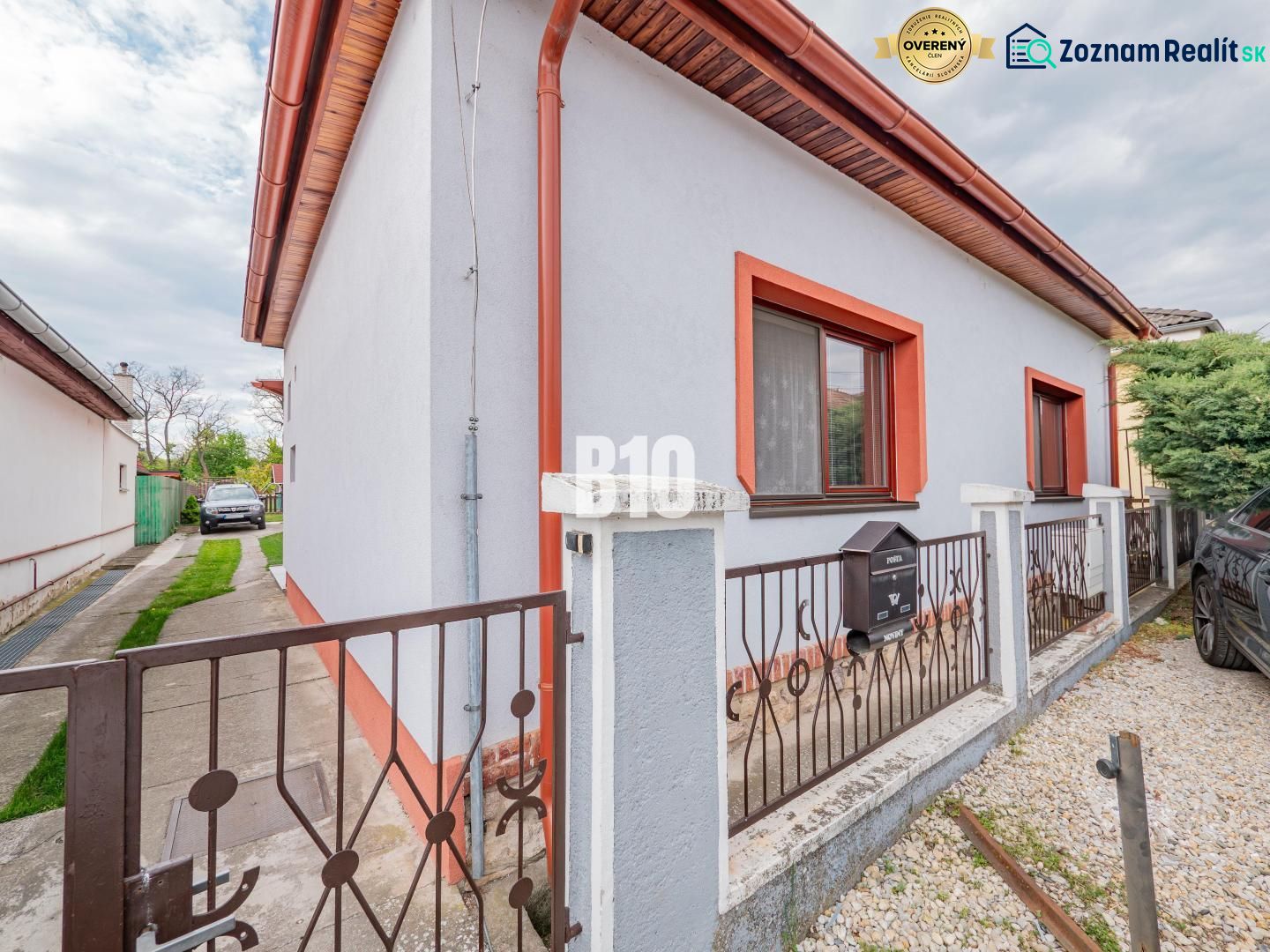 Prerobený dom, 981 m2 pozemok - Chrenová, Nitra (TOP lokalita) - Rodinný dom v Nitre s bielou fasádou, červeným lemovaním a záhradkou.