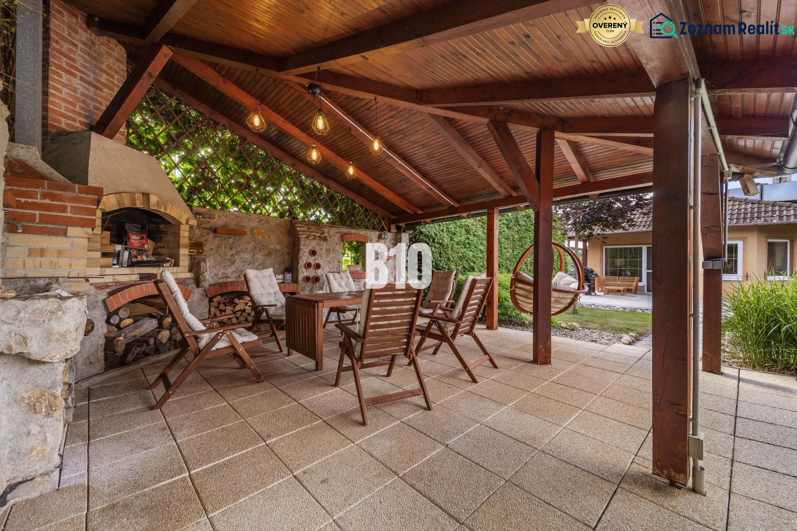 4i dom + 85 m² garáž | 5 min. od Nitry | Lehota | 230 m² | Bazén - Zastrešená terasa s krbom a drevenými stoličkami pri rodinnom dome v Nitre.