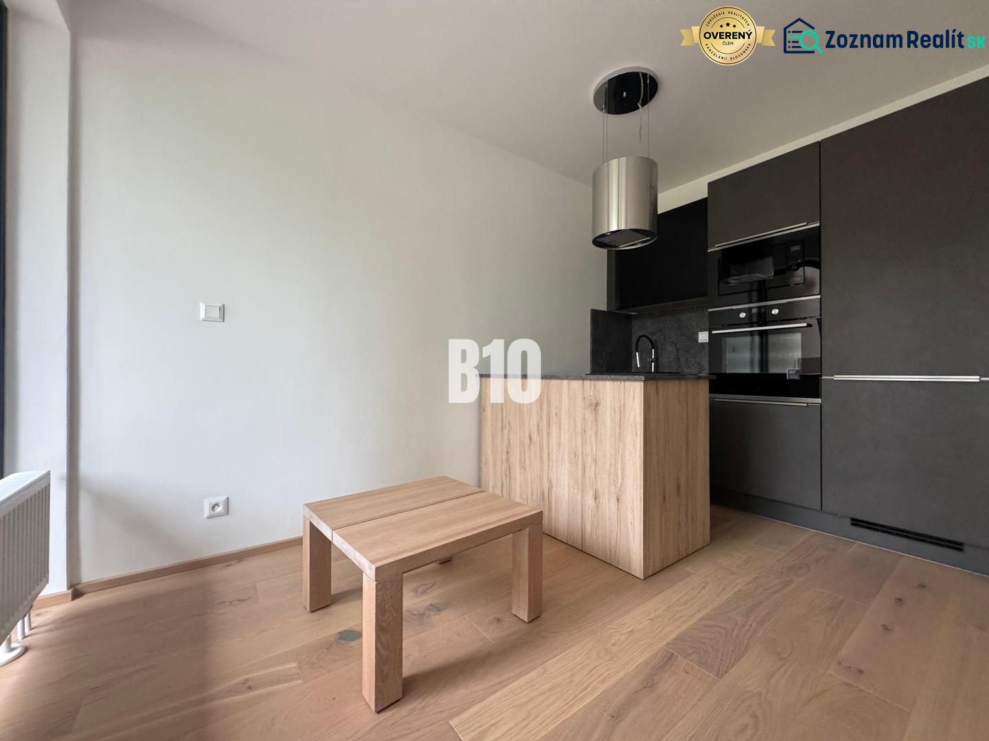 Relax Residence - Apartmán so zariadením - Kuchynský kút s tmavými skrinkami a podlahou s dreveným dekorom v 2-izbovom byte.