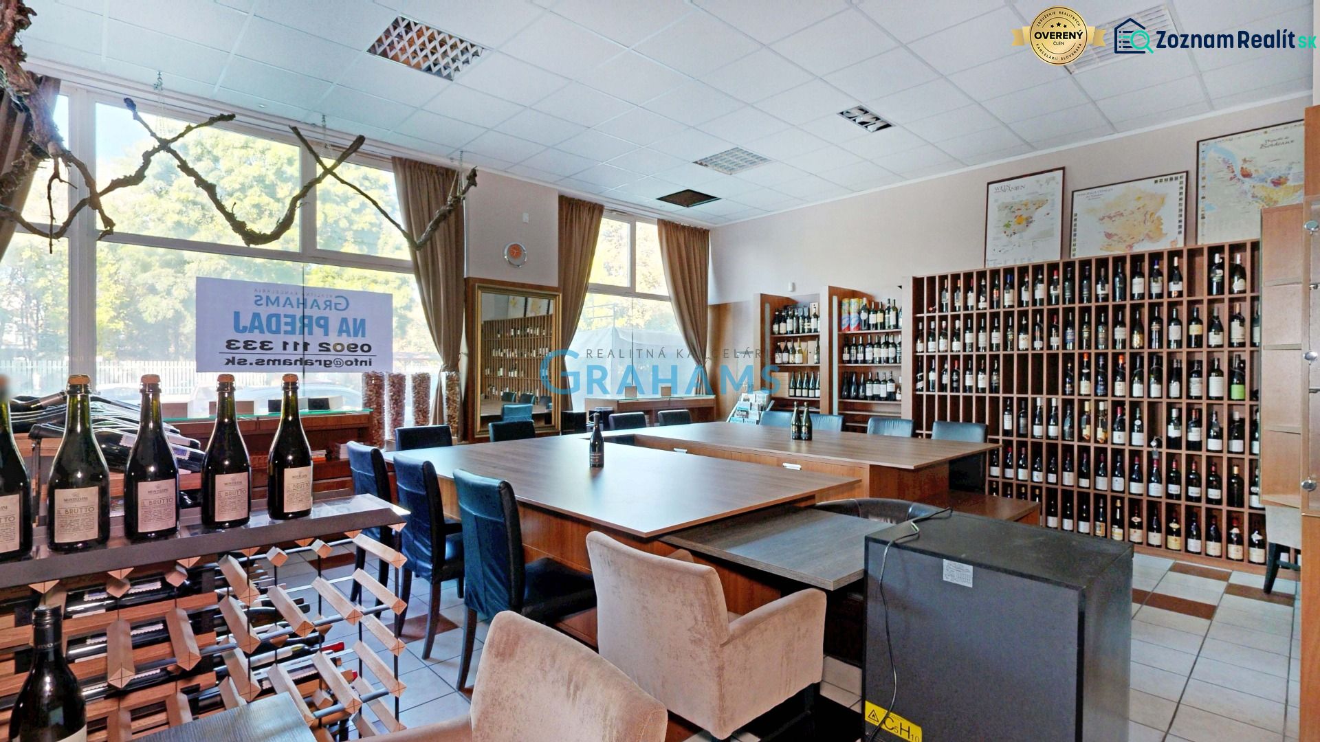 Klimatizovaný obchodný priestor - showroom alebo klinika,vstup z ulice - Interiér obchodných priestorov s vínnymi regálmi, fľašami vína a drevenými stolmi.