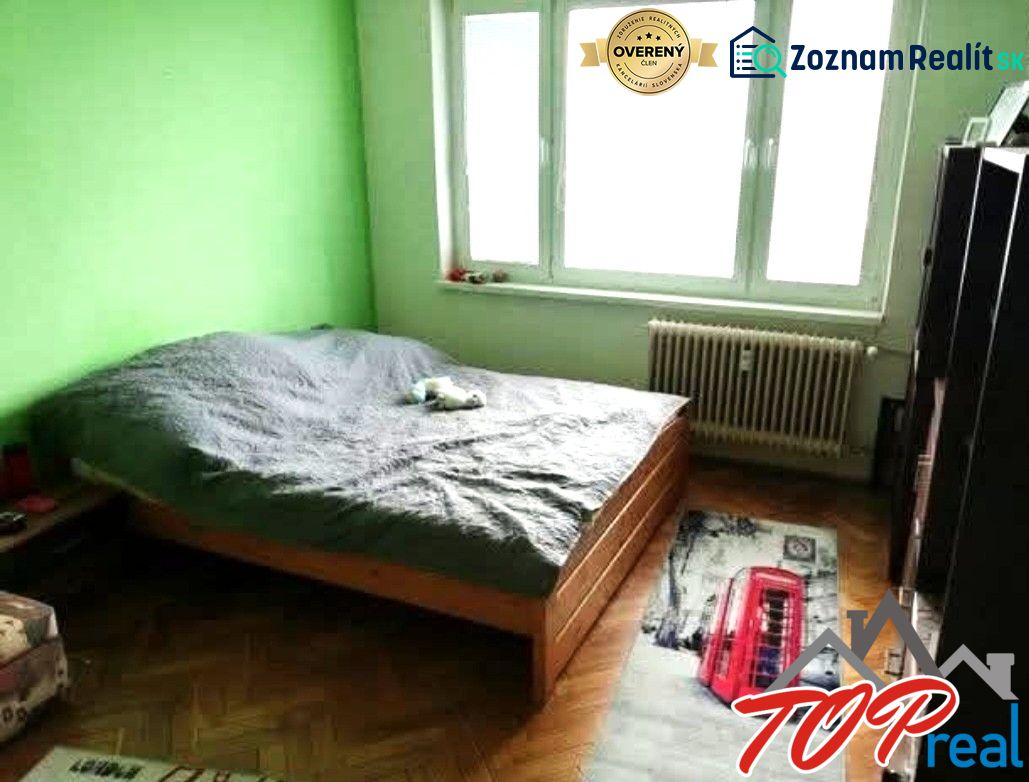 1- izbový byt - Košice - Juh, Ostravská ulica - Spálňa v 1-izbovom byte so zelenou stenou a podlahou s dreveným dekorom.