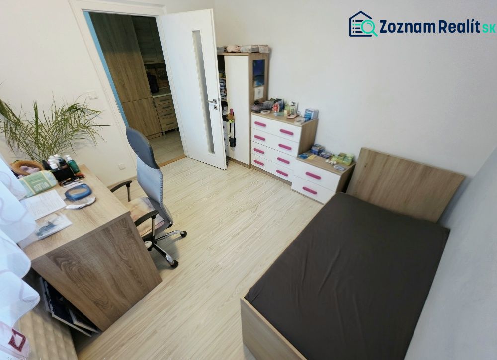 4 izbový byt Bánovce nad Bebravou /CENTRUM - STRED / 80 m2/ PIVNICA - Izba v 4-izbovom byte s dreveným dekorom podlahy, posteľou a písacím stolom.