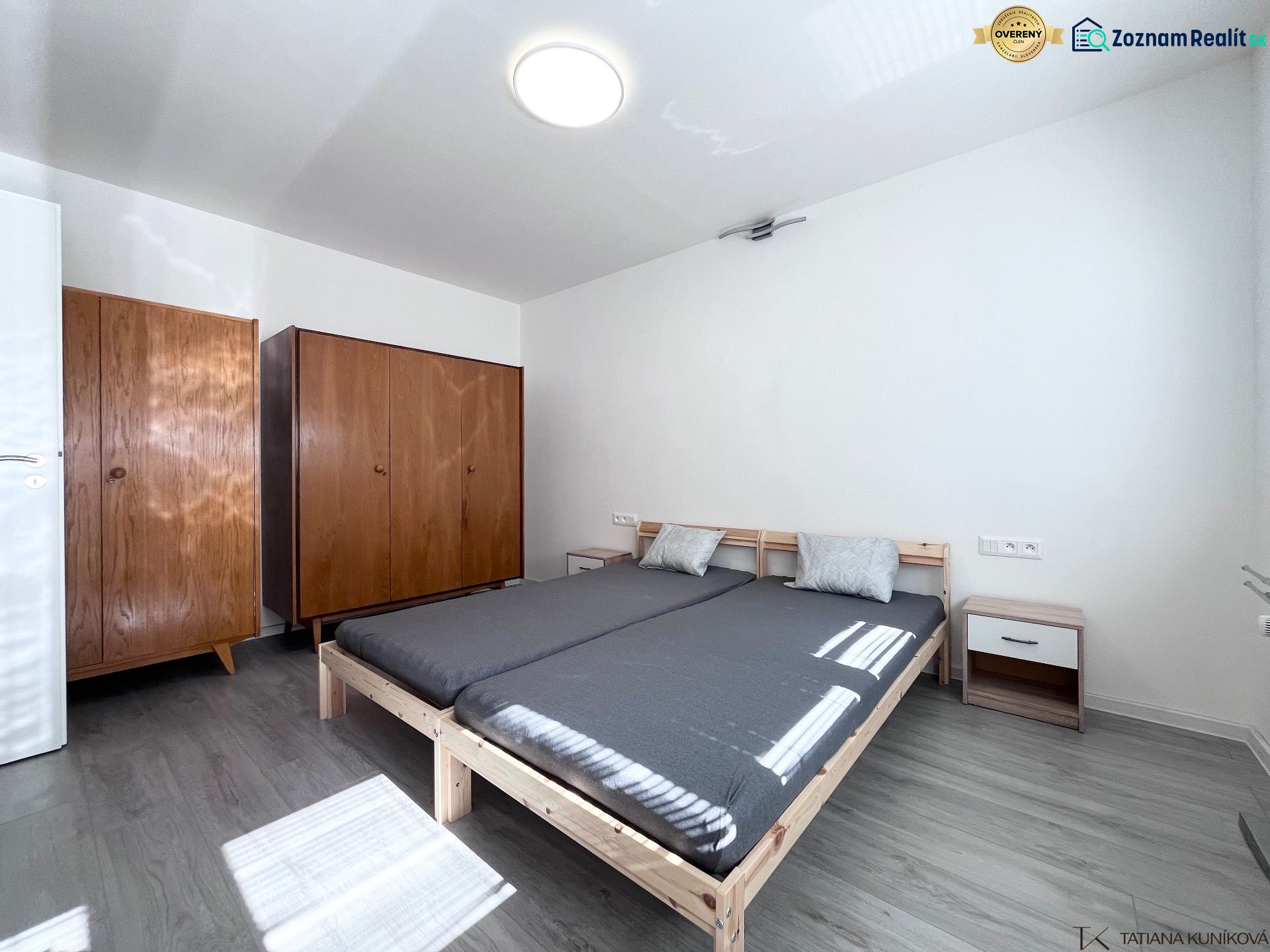NA PRENÁJOM! Slnečný a zariadený 3i byt 68 m2, ul. Švermova, Trenčín - Spálňa s posteľou, drevenými skriňami a podlahou s dreveným dekorom v 3-izbovom byte.
