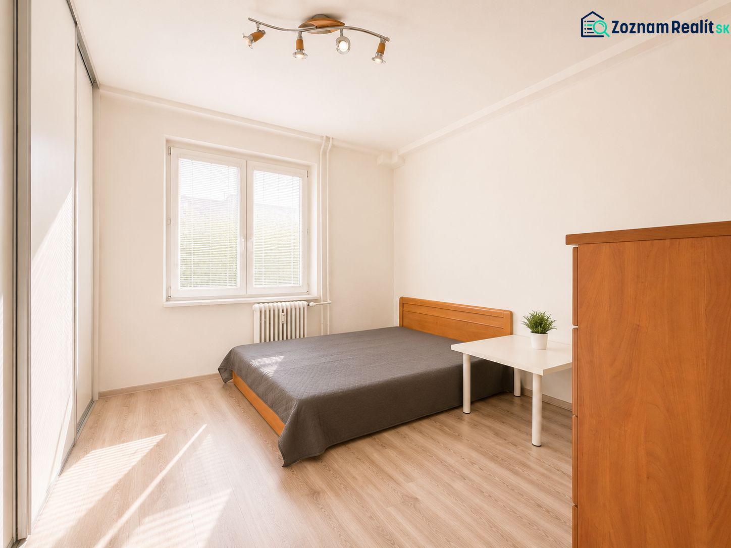 Na prenájom zariadený 4-izbový byt s balkónom I Ružinov |  - Spálňa v 4-izbovom byte s posteľou, skriňou a podlahou s dreveným dekorom.