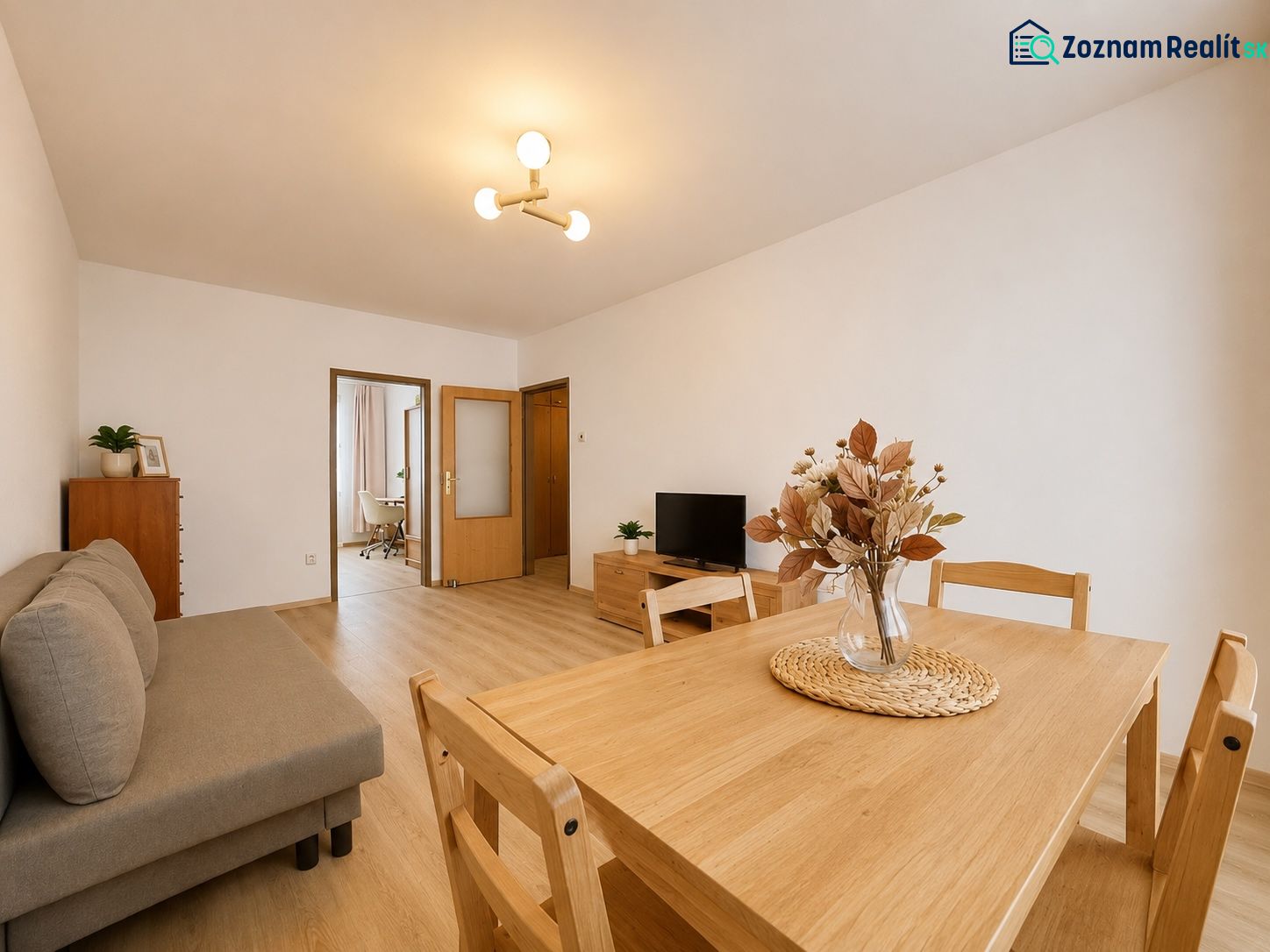Pekný zariadený 3-izbový byt s 2 balkónmi | 85,3 m² | Petržalka I - Obývačka v 3-izbovom byte s podlahou s dreveným dekorom, jedálenským stolom a pohovkou.