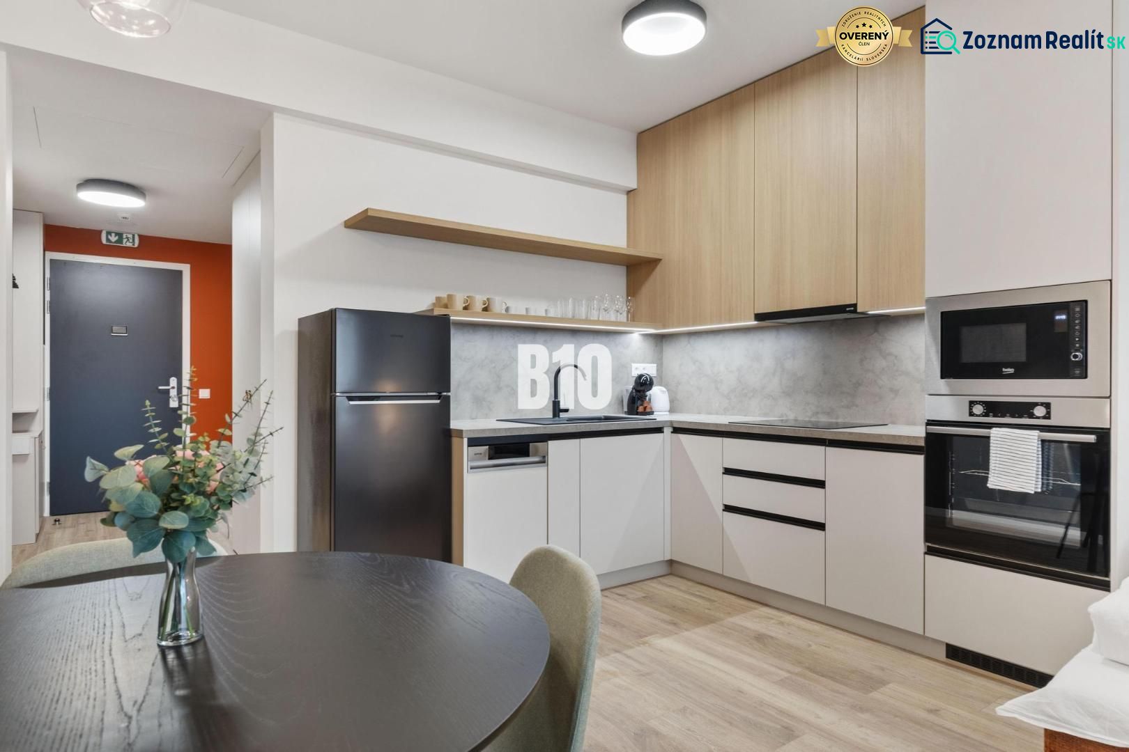 DOWNTOWN NA DOSAH – DIZAJNOVÝ 1-izbový apartmán s loggiou a výhľadom n - Kuchyňa s jedálenským stolom, spotrebičmi a podlahou s dreveným dekorom v 1-izbovom byte.