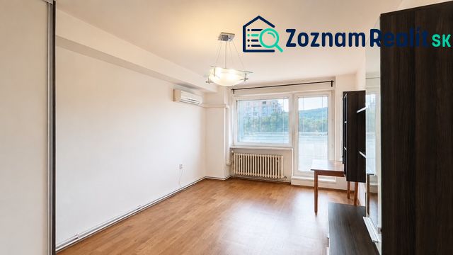 TOP Veľký rodinný 3-izbový byt s vlastným kúrením, loggiou a parkovaní - Obývacia izba s podlahou s dreveným dekorom, klimatizáciou a veľkým oknom v 3-izbovom byte.