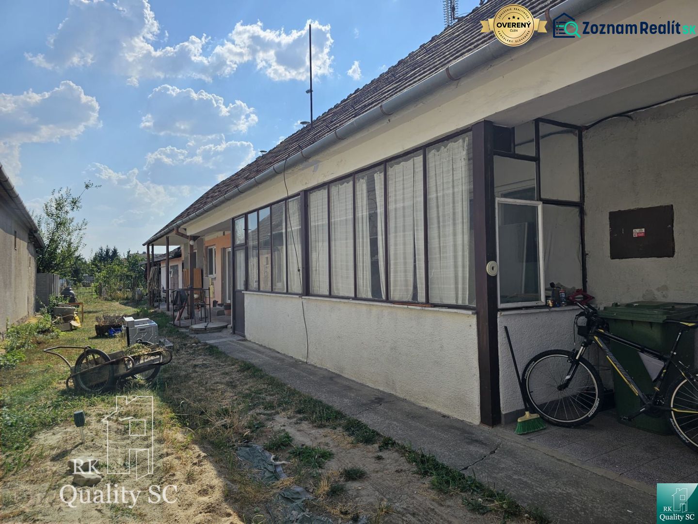 Okres Trnava- obec Pavlice – nehnuteľnosť s potenciálom - 4 izb. RD v  - Dvor rodinného domu v Pavliciach s prístreškom a bicyklom, obklopený trávnikom.