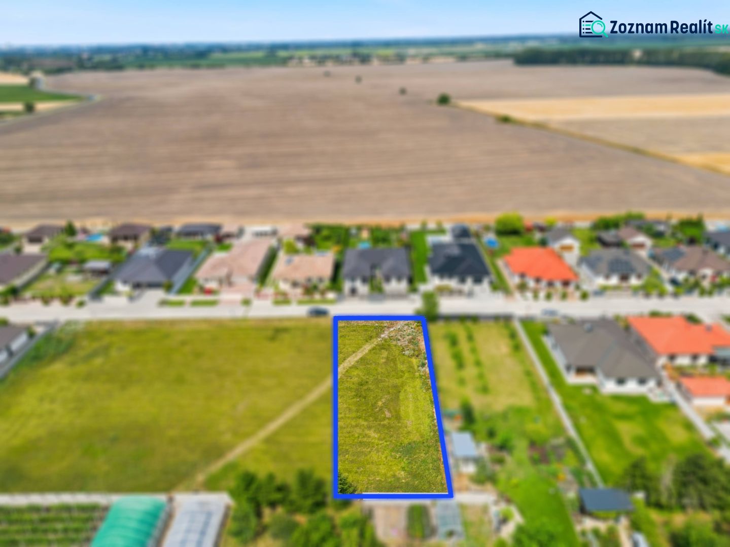 Stavebný pozemok v novej štvrti obce Ohrady – 969 m² - Pozemok v Ohradoch na neuvedenej ulici určený pre bývanie, obklopený domami a poľami.