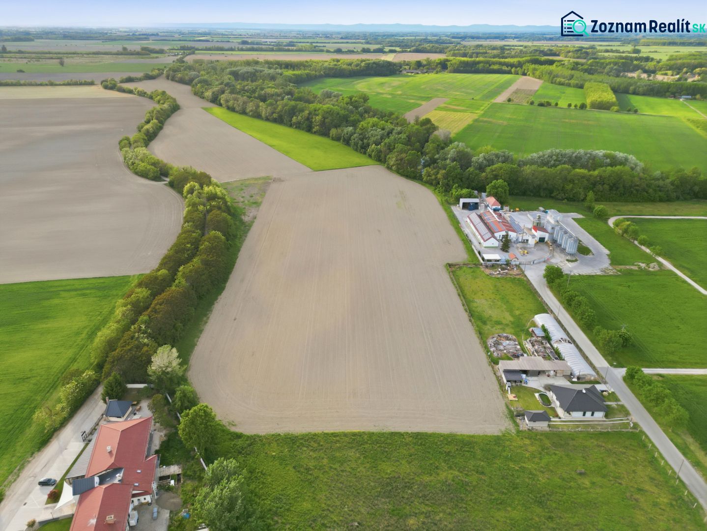 INVESTIČNÝ POZEMOK NA PREDAJ │ VÝNIMOČNÁ PRÍLEŽITOSŤ PRE INVESTOROV - Letecký pohľad na poľnohospodárske pozemky v Dunajskom Klátove, medzi ktorými vedie cesta.