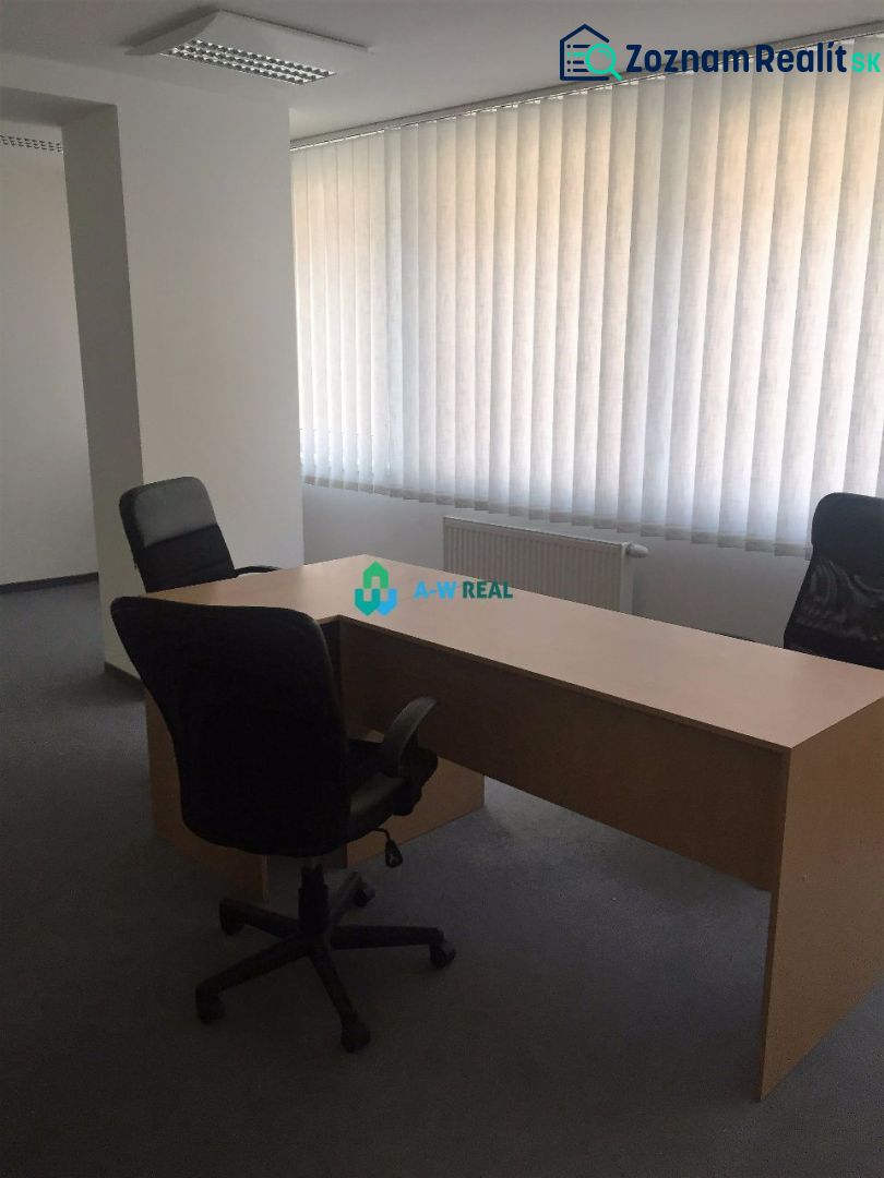 Kancelárie v centre mesta. - Jednoduchá kancelária s dreveným stolom, dvoma stoličkami a žalúziami na oknách.