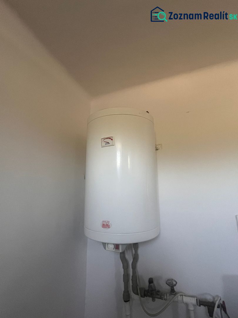 Rodinný dom okamžite obývateľný. - Biely elektrický bojler inštalovaný na stene v rodinnom dome.
