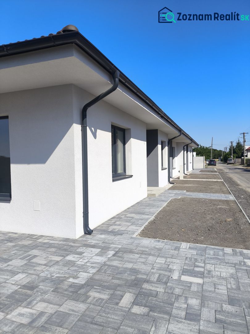 Moderný 4-izbový rodinný dom (dvojdom) v obci Vrakúň - Rodinný dom vo Vrakúni s výrazným chodníkom z dlažby a modrou oblohou.