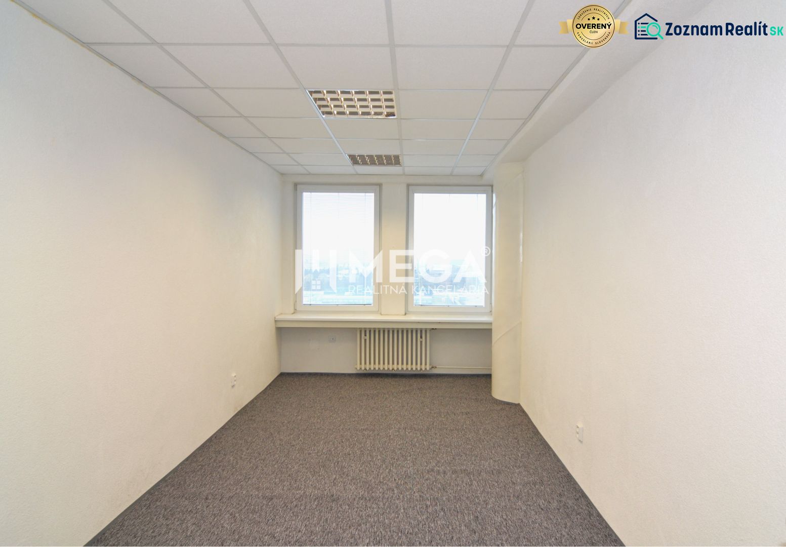 NA PRENÁJOM POSLEDNÉ VOĽNÉ kancelárie v centre mesta – 17,5 m² - Interiér kancelárie s bielymi stenami, kobercom a dvoma oknami.