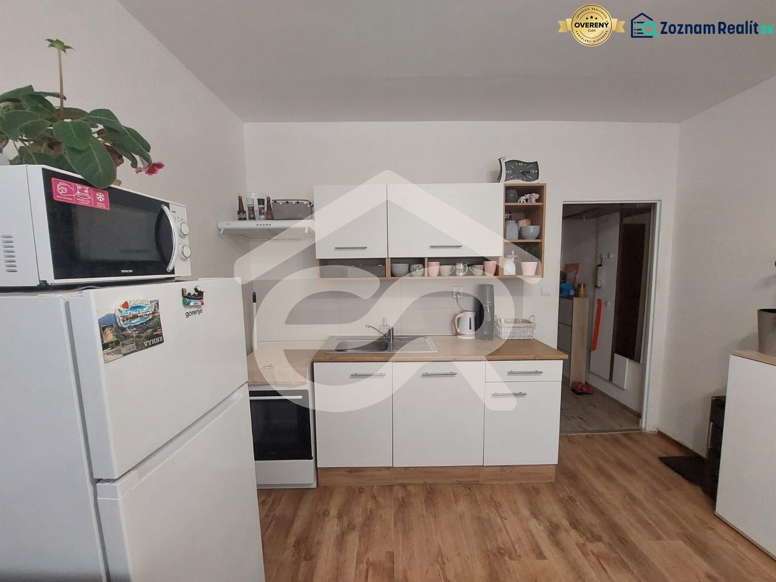 KOMPLETNE PREROBENÁ GARSÓNKA + PIVNICA: Nitra – Chrenová !  - Kuchyňa v garsónke s mikrovlnkou, chladničkou a podlahou s dreveným dekorom.
