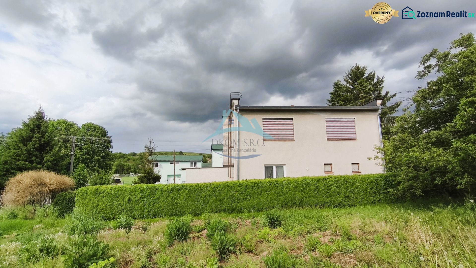 MIMORIADNE ZNÍŽENÁ CENA! Priestranný 6-izbový RD, Nenince, V. Krtíš. - Rodinný dom v Neninciach obklopený hustou zeleňou a stromami pod zamračenou oblohou.