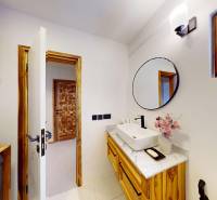 APARTMÁN NA PREDAJ V PAJE, ZANZIBAR - Kúpeľňa s dreveným umývadlom a zrkadlom, na ulici Paje a garsónka s kvetinami.