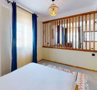 APARTMÁN NA PREDAJ V PAJE, ZANZIBAR - Interiér paje s prírodným drevom, bielymi stenami a závesmi, presvetlený garzónkou.