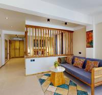 APARTMÁN NA PREDAJ V PAJE, ZANZIBAR - Garsónka na ulici s drevenými prvkami, modrou sedačkou a farebnými vankúšmi.