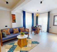 APARTMÁN NA PREDAJ V PAJE, ZANZIBAR - Svetlá garsónka s dreveným nábytkom a farebnými vankúšmi na ulici.