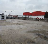 Spevnené plocha a lodné kontajnery v uzavretom areáli - Vajnory - Na ulici Pri starom letisku, pozemky - komerčné, prázdna plocha s budovami v pozadí.