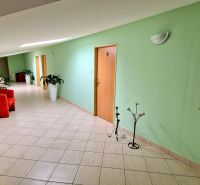 POLYFUNKČNÝ OBJEKT v Topoľčanoch NA PREDAJ - Chodba v budove s červenými kreslami, zelenými stenami, rastlinami. U Škultétyho.