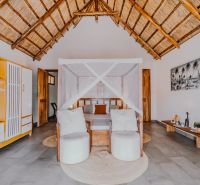 ZARIA GARDEN BUNGALOWS - Interiér izby so slamennou strechou, posteľou s baldachýnom a jednoduchou výstavbou domov.