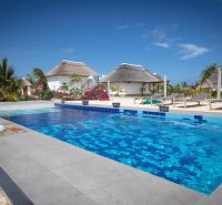 ZARIA GARDEN BUNGALOWS - Na obrázku vidno bazén, palmy a rekreačné domy s doškovými strechami v tropickom prostredí. Výstavba domov je vhodná pre relaxáciu.