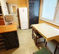 Na predaj : 3 izbový byt , centrum , Levice  - Kuchynská linka s čiernou skrinkou, bielou chladničkou a stolom v 3-izbovom byte.