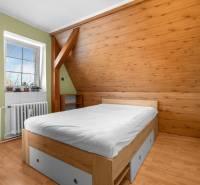 Priestranný 7-izbový dom na skok od centra – Senec - Drevenými obkladmi zdobená izba v rodinnom dome s drevenou posteľou a svetlými stenami.