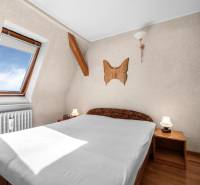 Priestranný 7-izbový dom na skok od centra – Senec - Spálňa v rodinnom dome s dreveným nábytkom, strešným oknom a dekoráciou na stene.