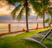 PARADISE OCEAN VIEW PATTAYA - Lehátka pri mori obklopené palmami počas západu slnka vo výstavbe bytov v Pattayi.