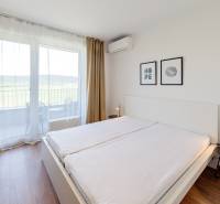 Krásny, elegantný 2i byt 52m2, lodžia, A/C, parking, BORY NA HRÁDZI - Spálňa v 2-izbovom byte s veľkým oknom, posteľou a nočným stolíkom.