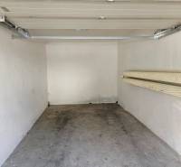 (16 m²) GARÁŽ NA PRENÁJOM V CENTRE - Interiér garáže s otvorenou bránou a vešiakmi na stene.