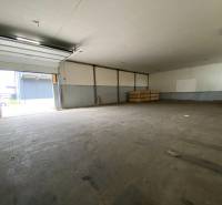Skladová hala, Žilina - Bánová - Prázdna hala s otvorenou bránou, skladovacie krabice na zemi v priemyselnom priestore.