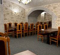 ODSTÚPENIE REŠTAURÁCIE v Nitre - Klenutý gastro priestor s kamennými stenami, dreveným stolom a elegantnými stoličkami.