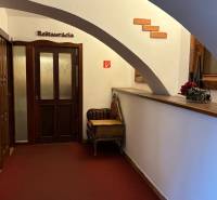 ODSTÚPENIE REŠTAURÁCIE v Nitre - Chodba s drevenými dverami vedie do reštaurácie, zdobená je stenou z tehál.